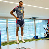 Jonathan Tah springt  im FC Bayern Trainingsoutfit