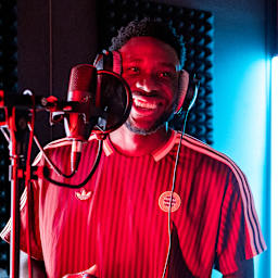 Alphonso Davies steht vor einem Mikro und lacht