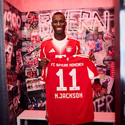 Nicolas Jackson hält ein FC Bayern Trikot mit der Nummer 11 und N. Jackson