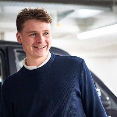 Jonas Urbig steigt aus einem Auto und lächelt.