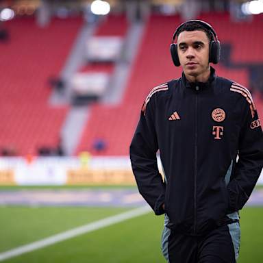 Jamal Musiala mit Kopfhörern auf dem Rasen vor Anpfiff des Bundesliga-Spiels des FC Bayern in Leverkusen.