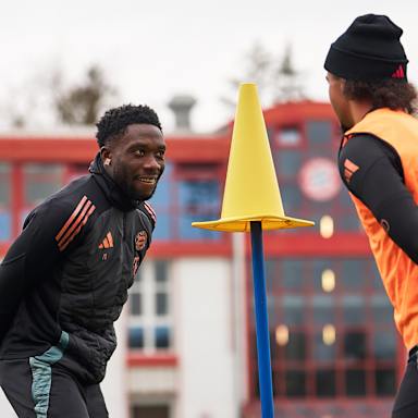 Alphonso Davies und Leroy Sané blicken auf ein Hütchen auf einer Stange im FC Bayern-Training vor dem Bundesliga-Spiel bei Union Berlin