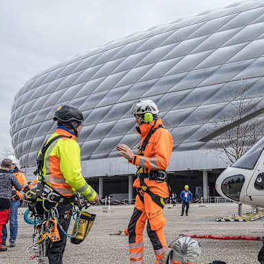 Piloten sprechen vor der Allianz Arena, daneben ein Hubschrauber