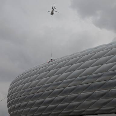 Ein Hubschrauber schwebt über der Allianz Arena und seilt seine Ladung ab