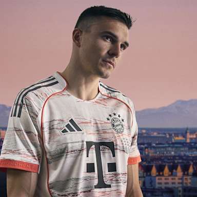 Joao Palhinha im neuen Auswärtstrikot des FC Bayern für die Saison 2025/26 in Weiß, Grau und leuchtendem Coral.