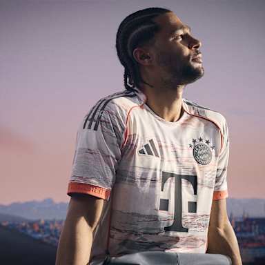 Serge Gnabry im neuen Auswärtstrikot des FC Bayern für die Saison 2025/26 in Weiß, Grau und leuchtendem Coral.