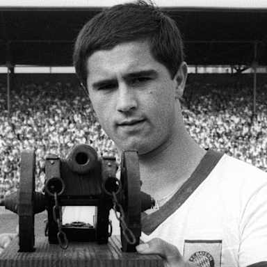 Gerd Müller betrachtet die Torjägerkanone, die er überreicht bekommen hat.