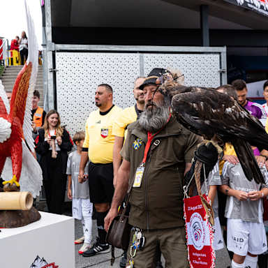 Ein Adler wird auf das Felf geführt vor dem Traumspiel des FC Bayern gegen den Fanclub Red Eagles Austria.