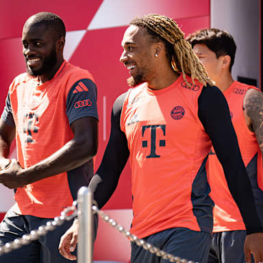 Dayot Upamecano und Sacha Boay lächelnd auf dem Weg zum Trainingsplatz des FC Bayern.