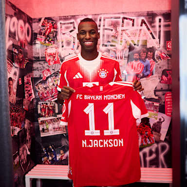 Nicolas Jackson hält ein FC Bayern Trikot mit der Nummer 11 und N. Jackson