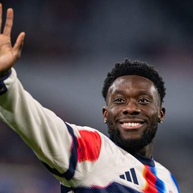 Alphonso Davies winkt vor dem Spiel gegen Sporting zu den Fans und lacht
