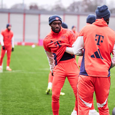 Alphonso Davies greift sich auf dem Rasen unter das Shirt im Training des FC Bayern