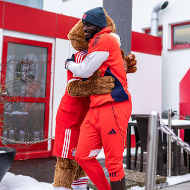 Dayot Upamecano umarmt Maskottchen Berni vor dem öffentlichen Training des FC Bayern vor Fans