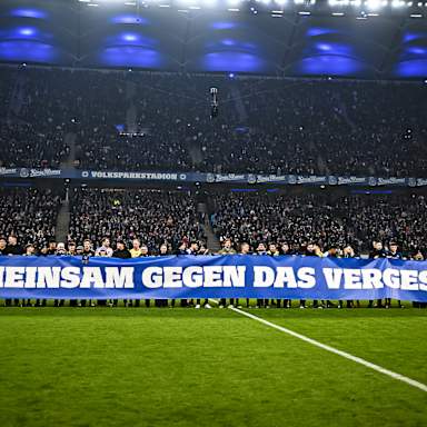 Spieler und Mitarbeiter beider Vereine halten ein Banner vor dem Gastspiel des FC Bayern in der Bundesliga beim Hamburger SV