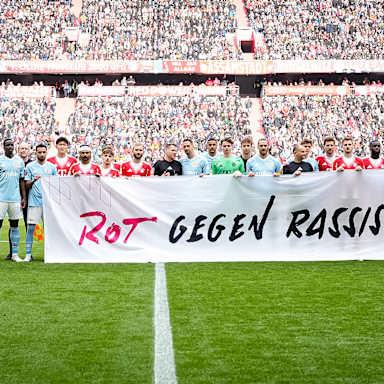 Die Spieler halten ein Banner mit der Aufschrift "Rot gegen Rassismus" vor dem Heimspiel des FC Bayern in der Bundesliga gegen den 1. FC Union Berlin