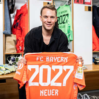 Manuel Neuer hält ein orangenes Torwarttrikot mit 2027 Neuer