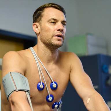 Manuel Neuer fährt auf dem Fahrradergometer mit Elektroden auf dem Oberkörper