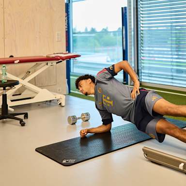 Nathaniel Brown macht einen Seitstütz im FC Bayern Trainingsshirt