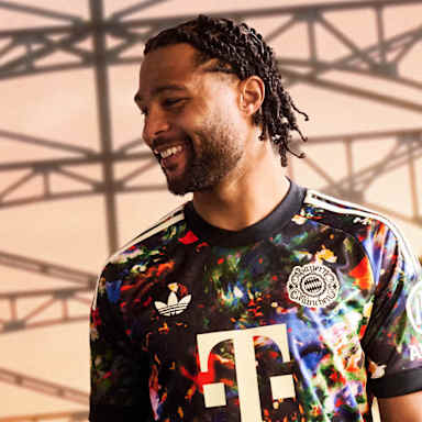 Serge Gnabry  trägt das neue FC Bayern-Wiesn-Trikot 2026/27 mit farbenfrohem floralen Muster, im Hintergrund ist die Münchner Hackerbrücke zu sehen