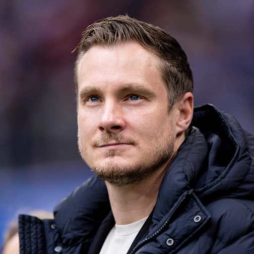 Marcell Jansen schaut in einer dunklen Jacke in Richtung Himmel.