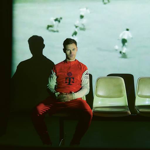 Joshua Kimmich beim TV-Abend - auf einer Leinwand hinter ihm sind Ausschnitte des Europapokalfinalsiegs 19767 zu sehen