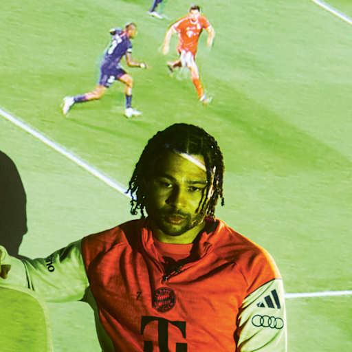 Serge Gnabry beim TV-Abend - auf einer Leinwand hinter ihm sind Ausschnitte großer Bayern-Triumphe zu sehen