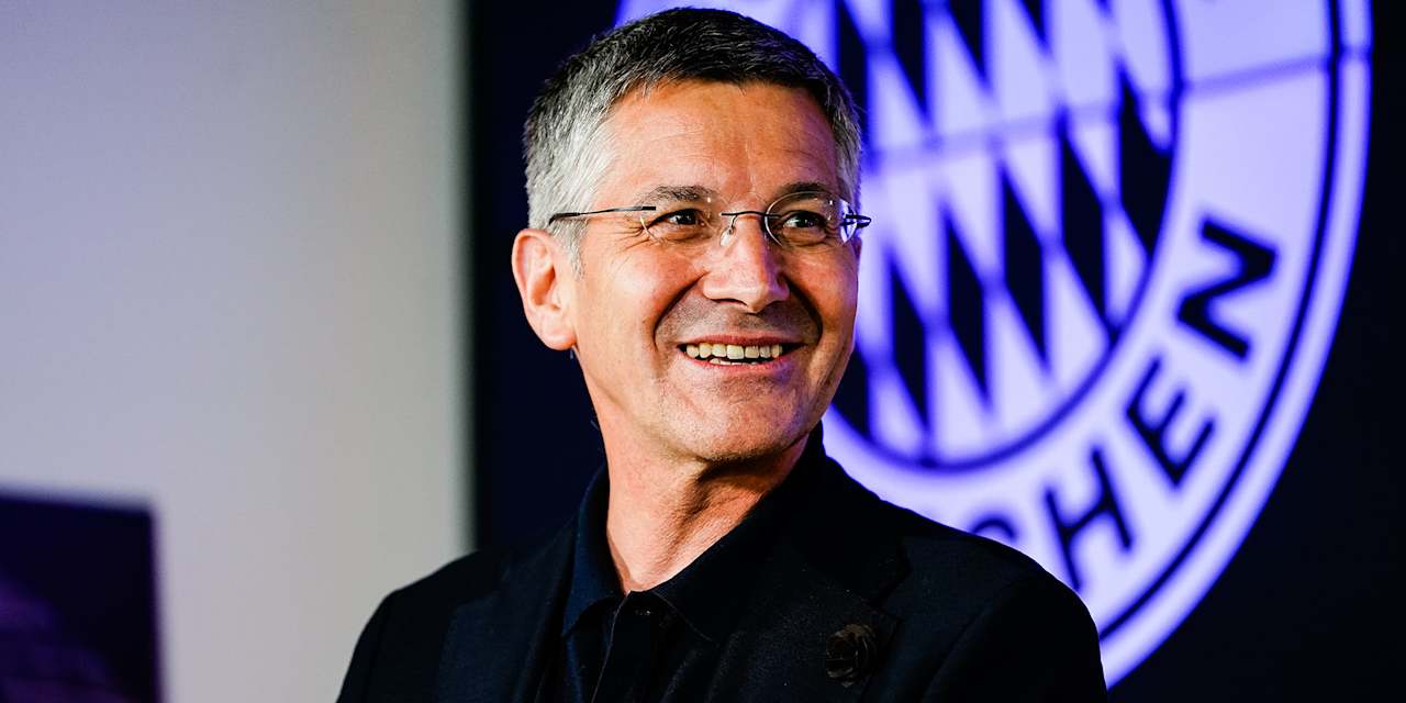 FC Bayern president smiling in front of the German record champions' badge