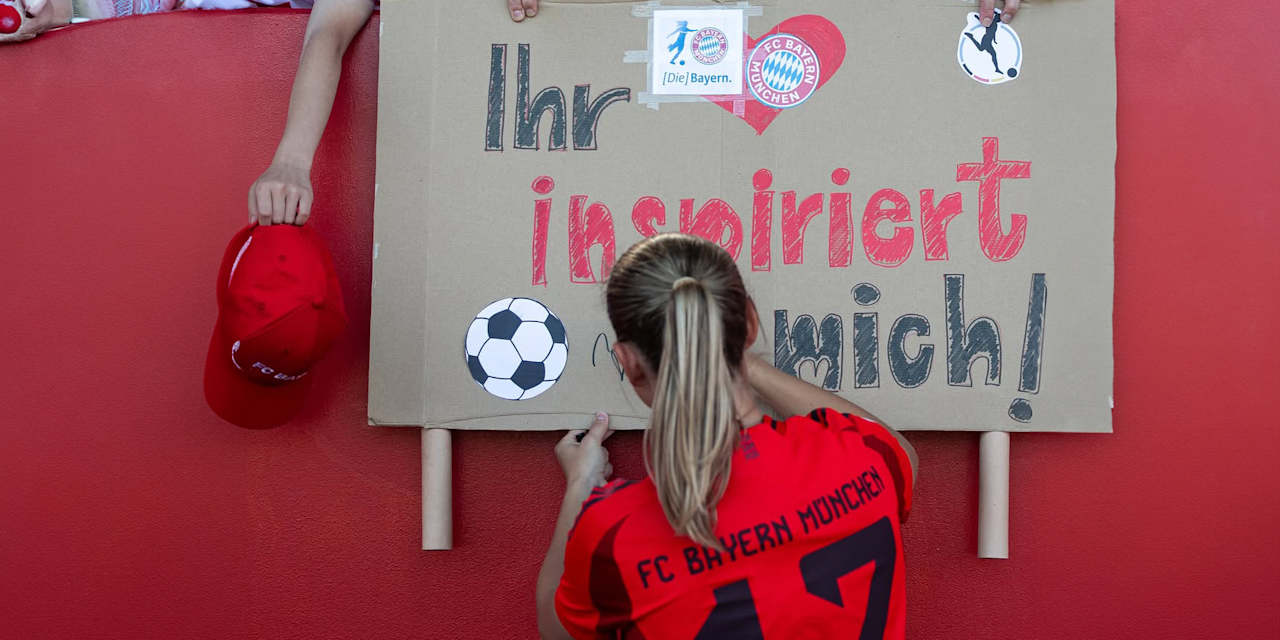 FC Bayern Women’s Klara Bühl signs a poster from a fan that says “You inspire me”.