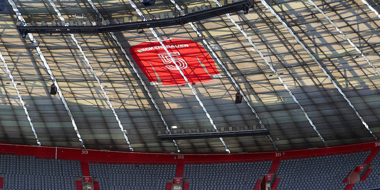 Ein rotes Trikot von Franz Beckenbauer mit einer weißen 5 hängt unter dem Dach der Allianz Arena