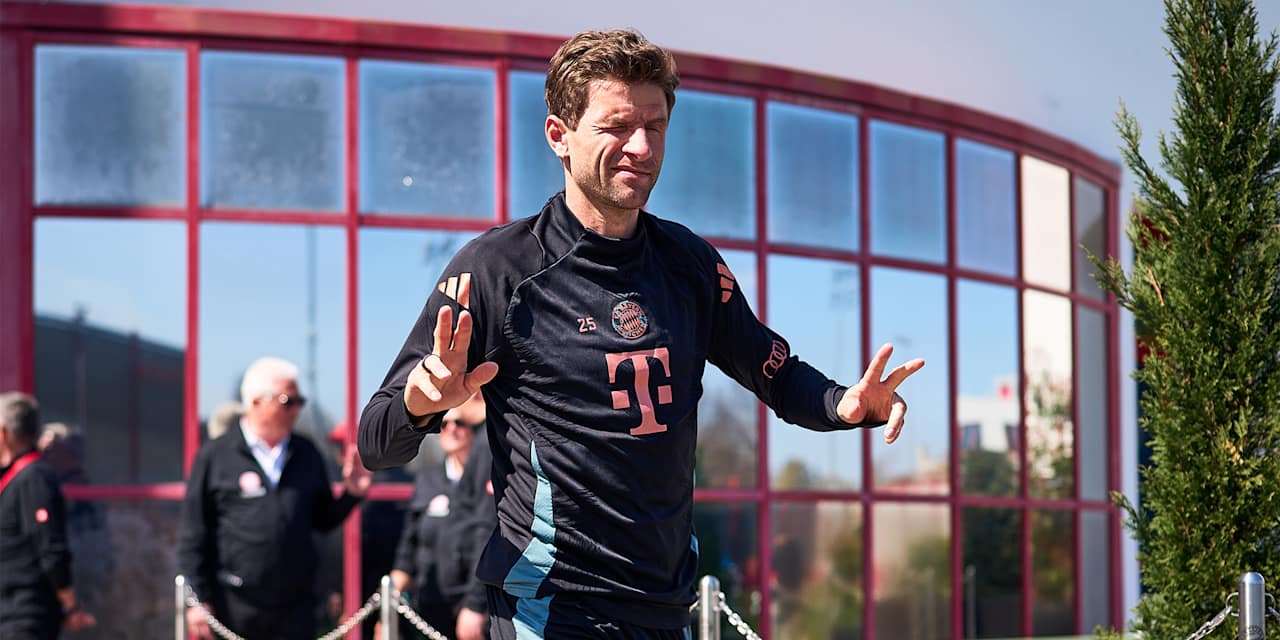 Thomas Müller zwinkert in die Kamera und zeigt das doppelte Victory-Zeichen vor dem Training des FC Bayern