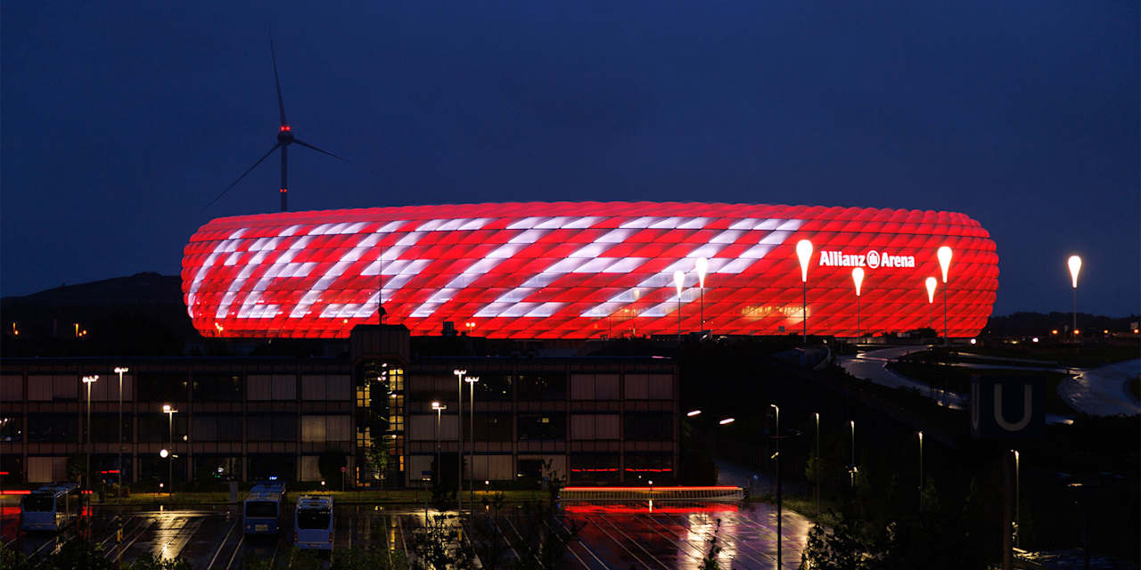 Allianz Arena leuchtet bei Nacht in Rot mit weißem Schriftzug Meister