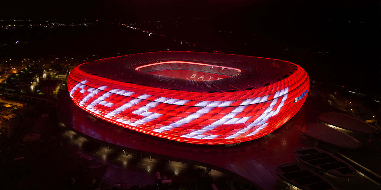 Allianz Arena leuchtet bei Nacht in Rot mit weißem Schriftzug Meister