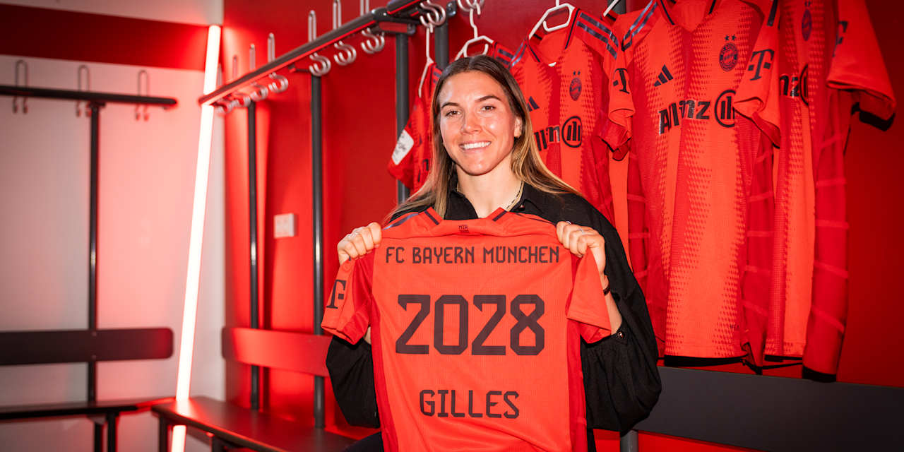 Vanessa Gilles smiles holding the FC Bayern shirt with her name and contract expiry year 2028.