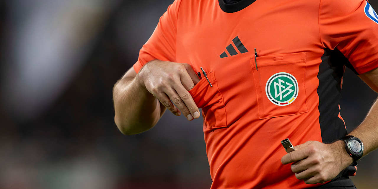 Ein Bundesliga-Schiedsrichter zieht die gelbe Karte aus der Brusttasche.