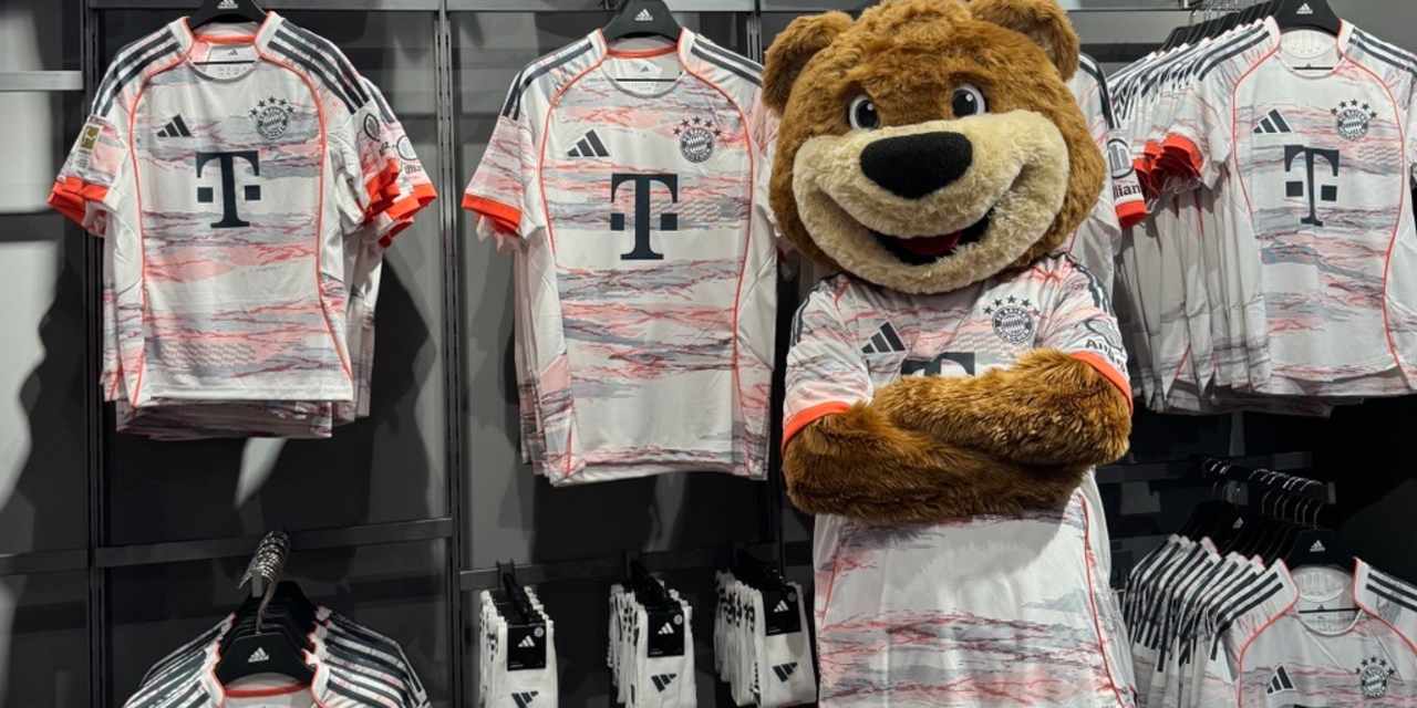 Berni vor dem Tor an der Säbener Straße. Erhält einen Schal hoch und stützt ein Bein auf dem Ball ab.