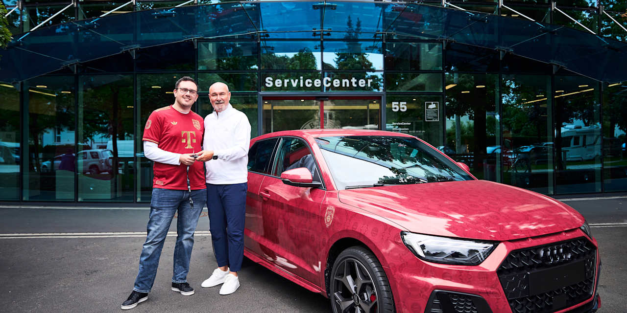 Raimond Aumann hands over a red Audi A1 to a fan at Säbener Strasse
