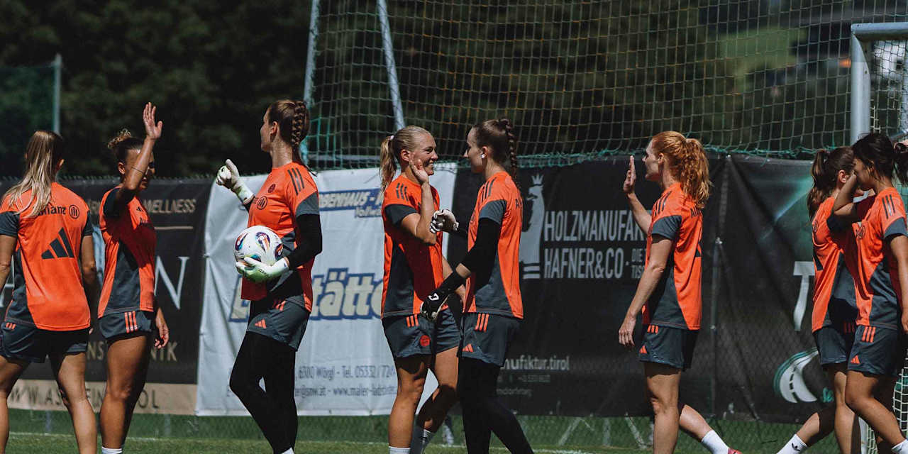 FC Bayern Women players high-five each other on the training pitch.