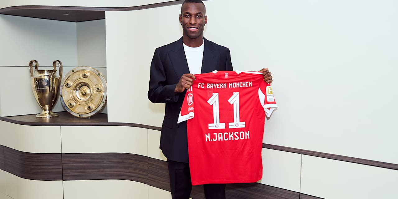 Nicolas Jackson hält ein FC Bayern Trikot mit der Nummer 11 und N. Jackson