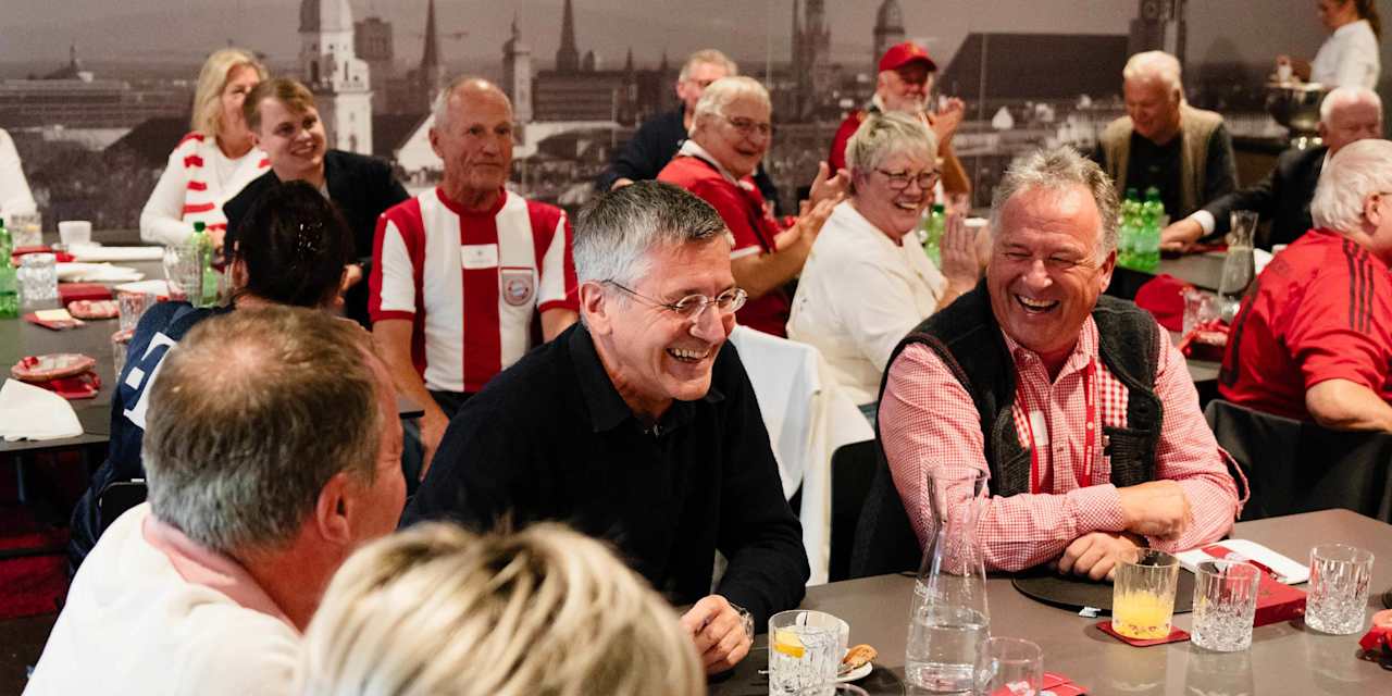 Herbert Hainer lacht inmitten von FC Bayern-Fans