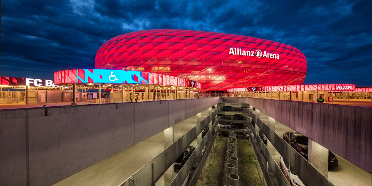 Rot erleuchtete Allianz Arena und Parkhäuser