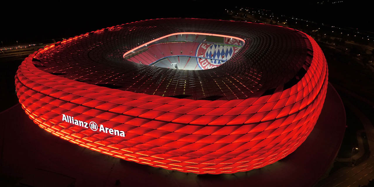 The Allianz Arena lit up in red at night from a birds-eye view.