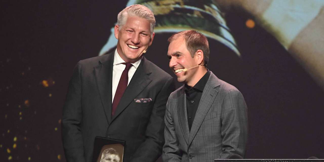 Bastian Schweinsteiger and Philipp Lahm laughing in suits