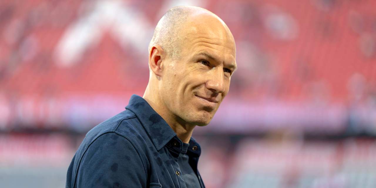 Arjen Robben grinst in einem blauen Hemd in die Kamera.