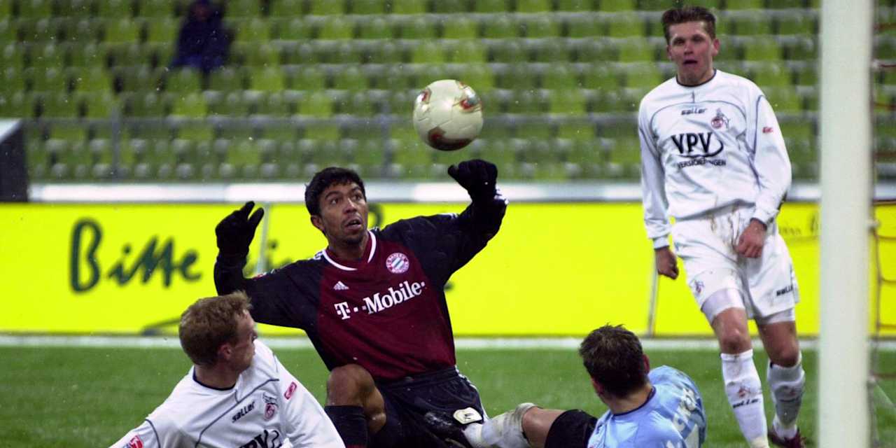 Giovane Elber blickt beim  Pokalspiel gegen Köln am Boden hockend auf dem Ball, umringt von liegenden Kölnern