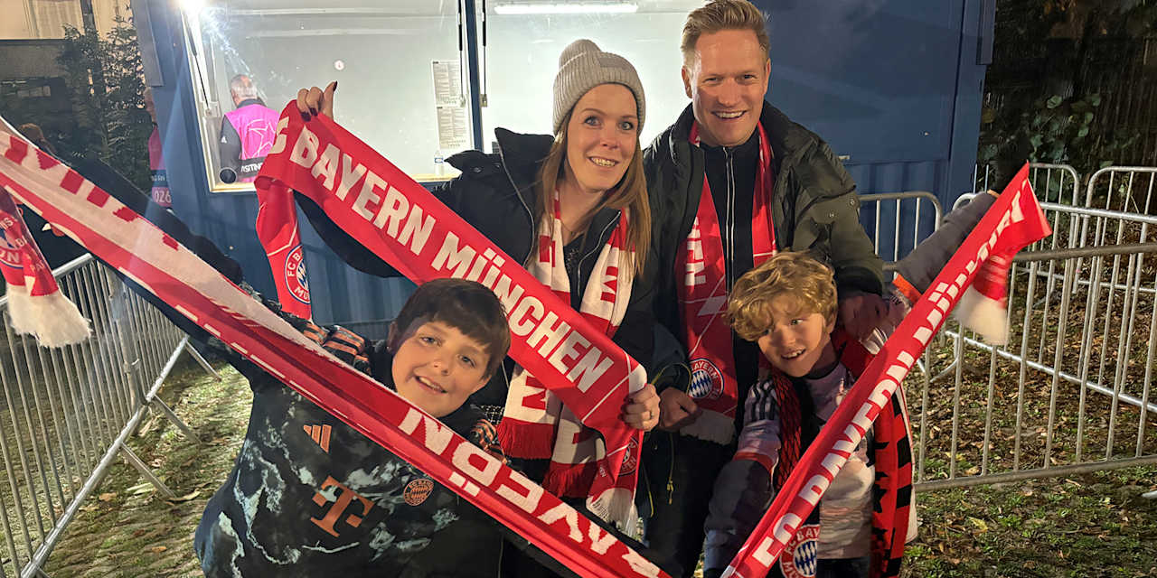 Eine Familie aus Fans des FC Bayern strecken ihre Schals in die Höhe