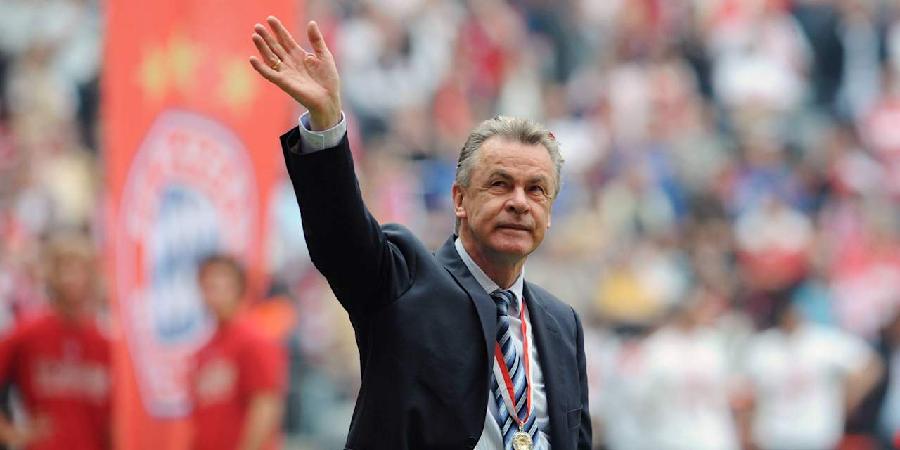 Ottmar Hitzfeld winkt ins Publikum, links eine Bayern-Fahne