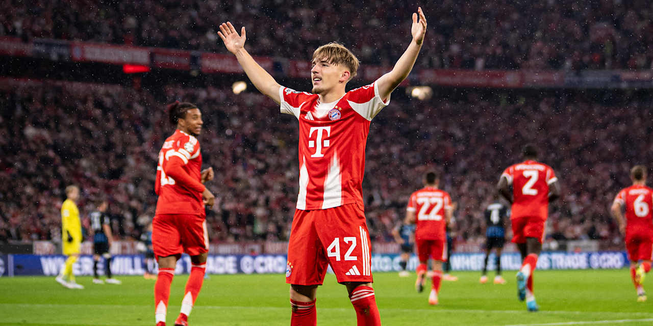 Nach seinem 1. Champions League-Tor für den FC Bayern gegen Club Brügge steht Lennart Karl mit ausgebreiteten Armen vor der Fankurve.