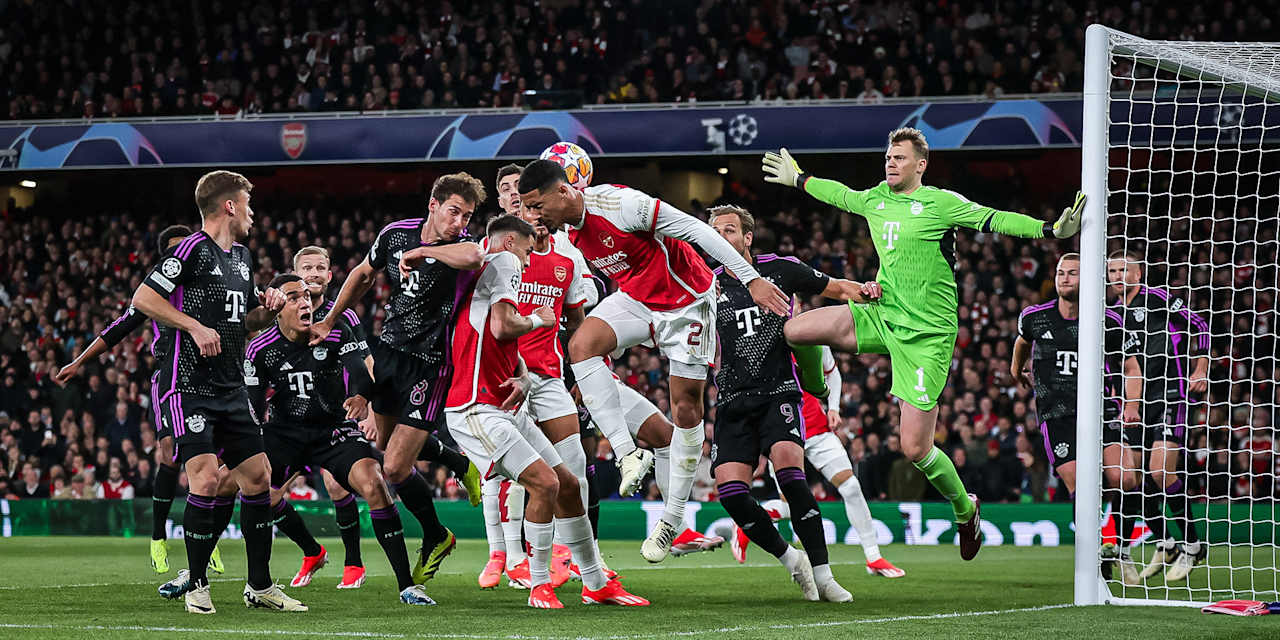 Verschiedene FC Bayern-Spieler in Schwarz und Arsenal-Spieler in Rot gehen zum Ball. Manuel Neuer steht in Grün im Tor.