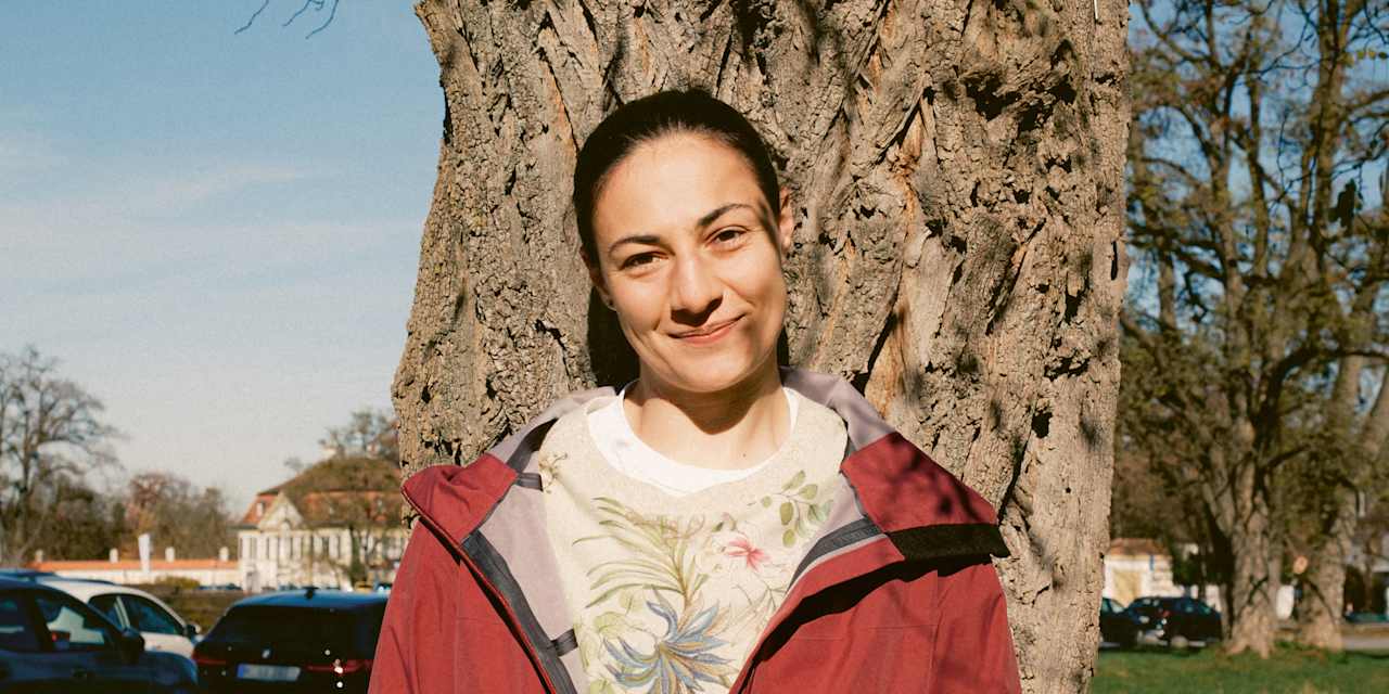 Mala Grohs steht vor einem Baum und lächelt.
