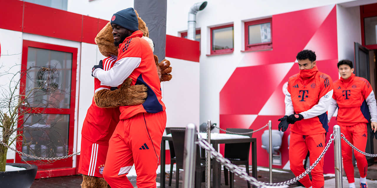 Dayot Upamecano umarmt Maskottchen Berni vor dem öffentlichen Training des FC Bayern vor Fans